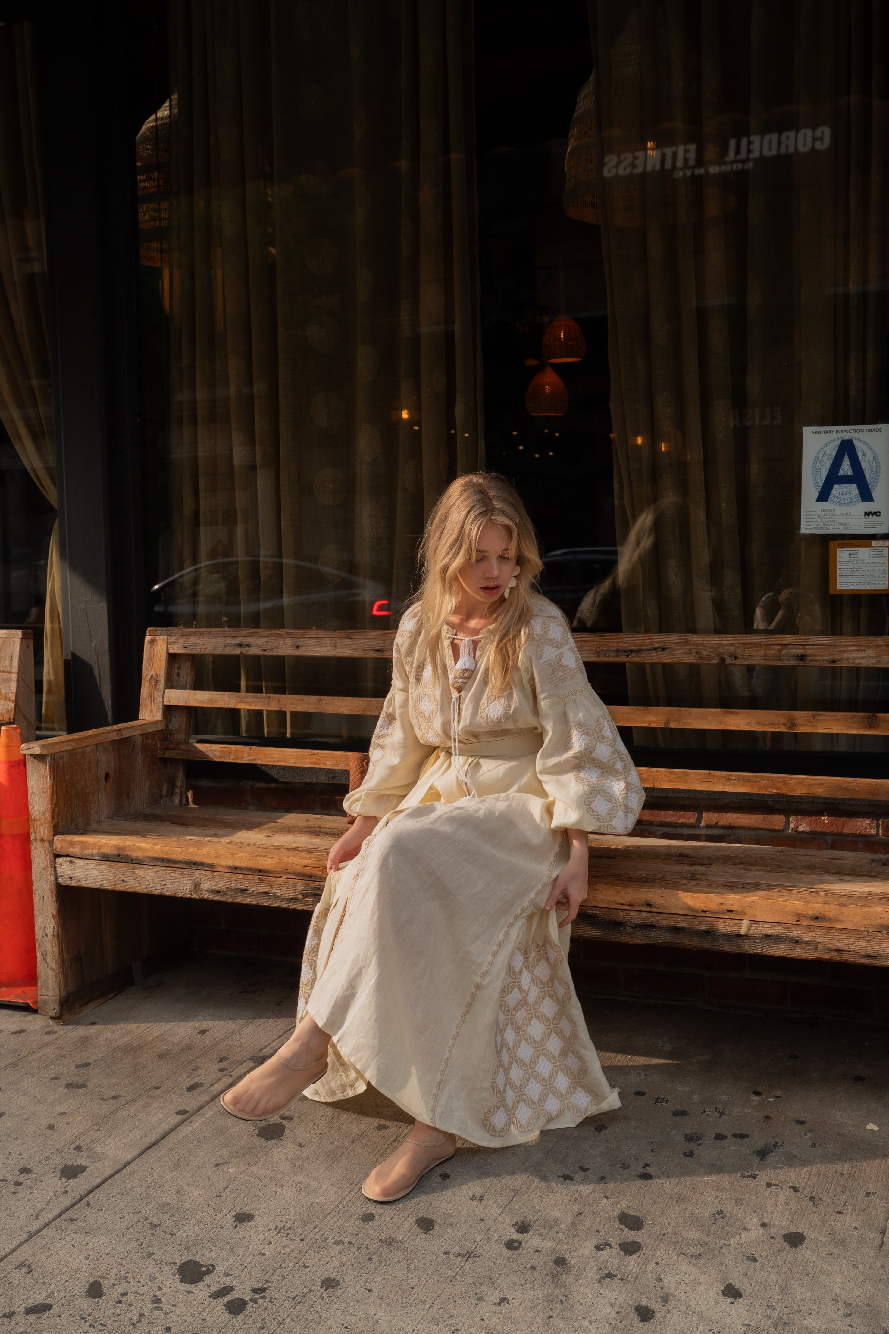 ANNABO Svitanok maxi dress in cream beige linen with geometric embroidery, voluminous sleeves, tasseled neckline ties, and flowing maxi silhouette. Crafted from 100% linen in a timeless artisanal-inspired design.
